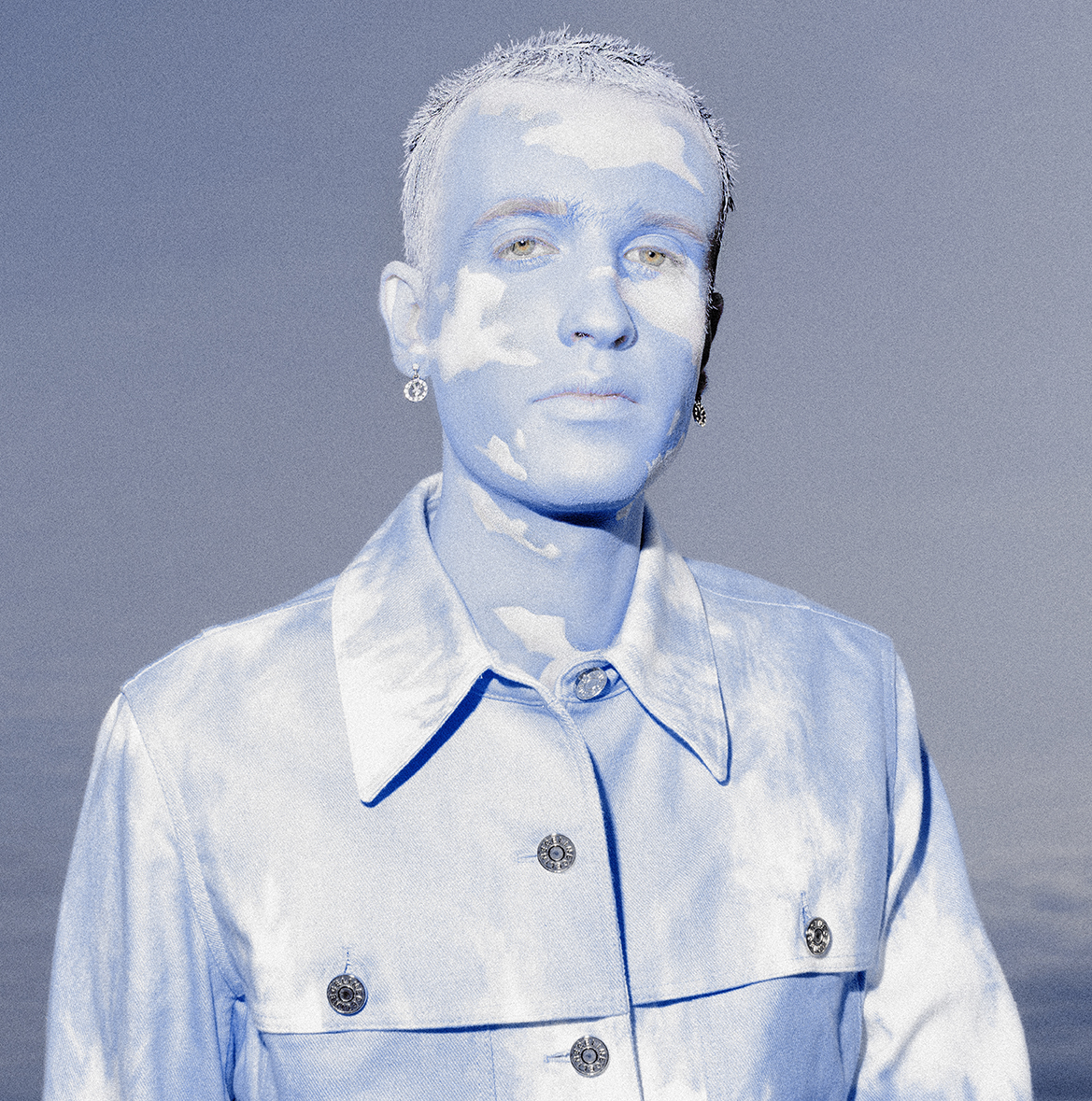 Jesse Clark with cloud themed facepaint photographed against a blue sky